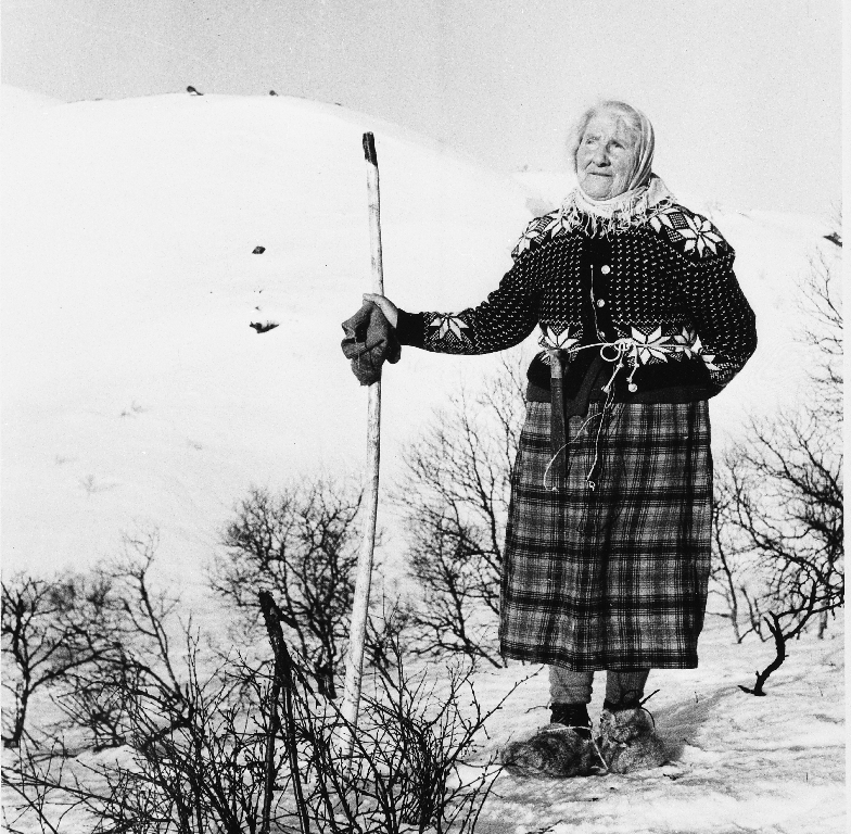 Gunnhild Kvinen i snareskog. Ho har kniv i beltet og "lampar" på føtene. Lampane er laga av kuhår, hestetagl og ull. (nålebinding)
