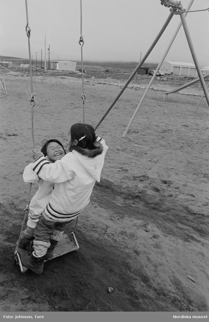 Arktis. Lappland. Två barn gungnar fram och tillbaka. Barn leker ute.