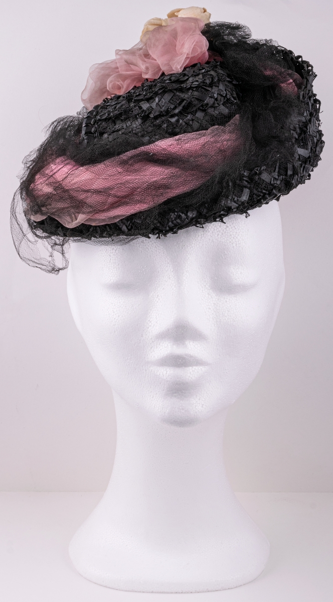 Hatt av svarta pärlor, garnerad med skära rosenknoppar, rosa chiffong, svart tyll och stenkolsspänne.