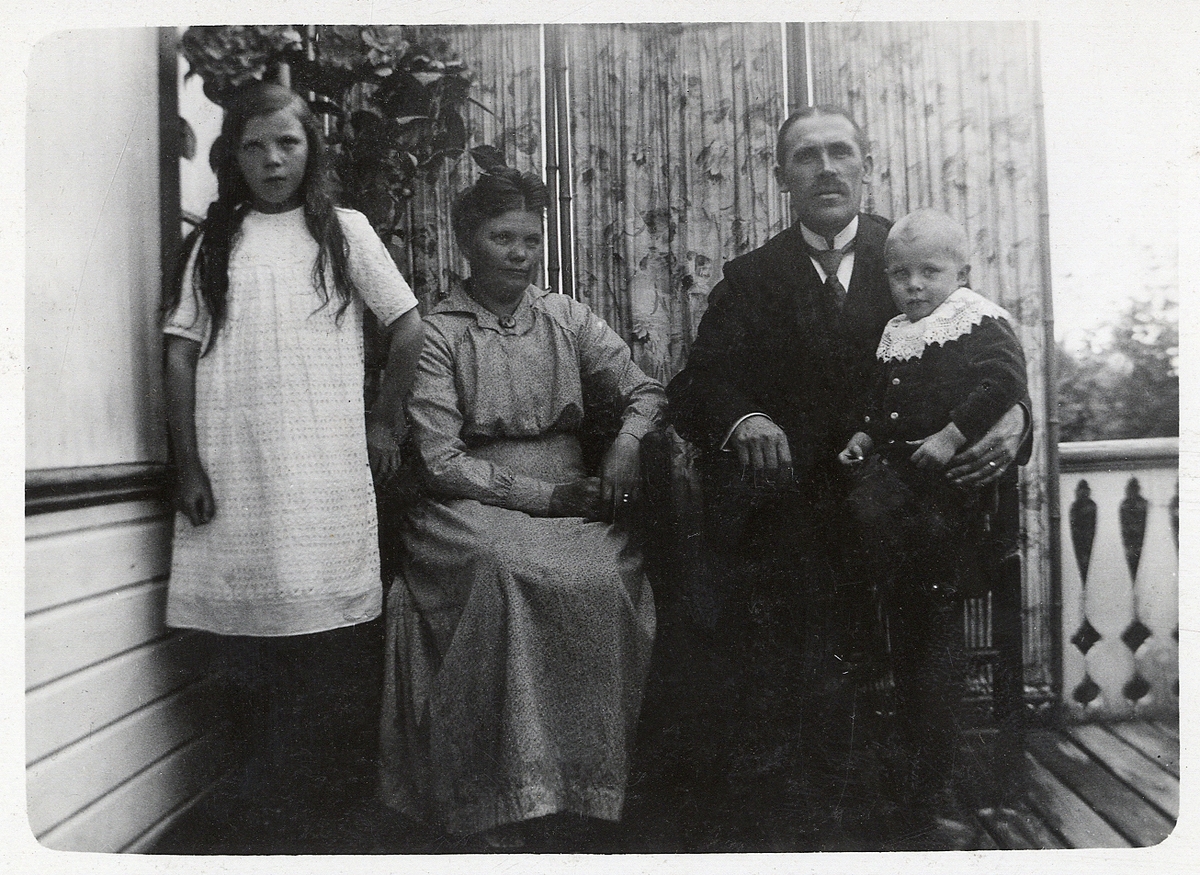 En okänd familj, bestående av far, mor och två barn på en veranda.