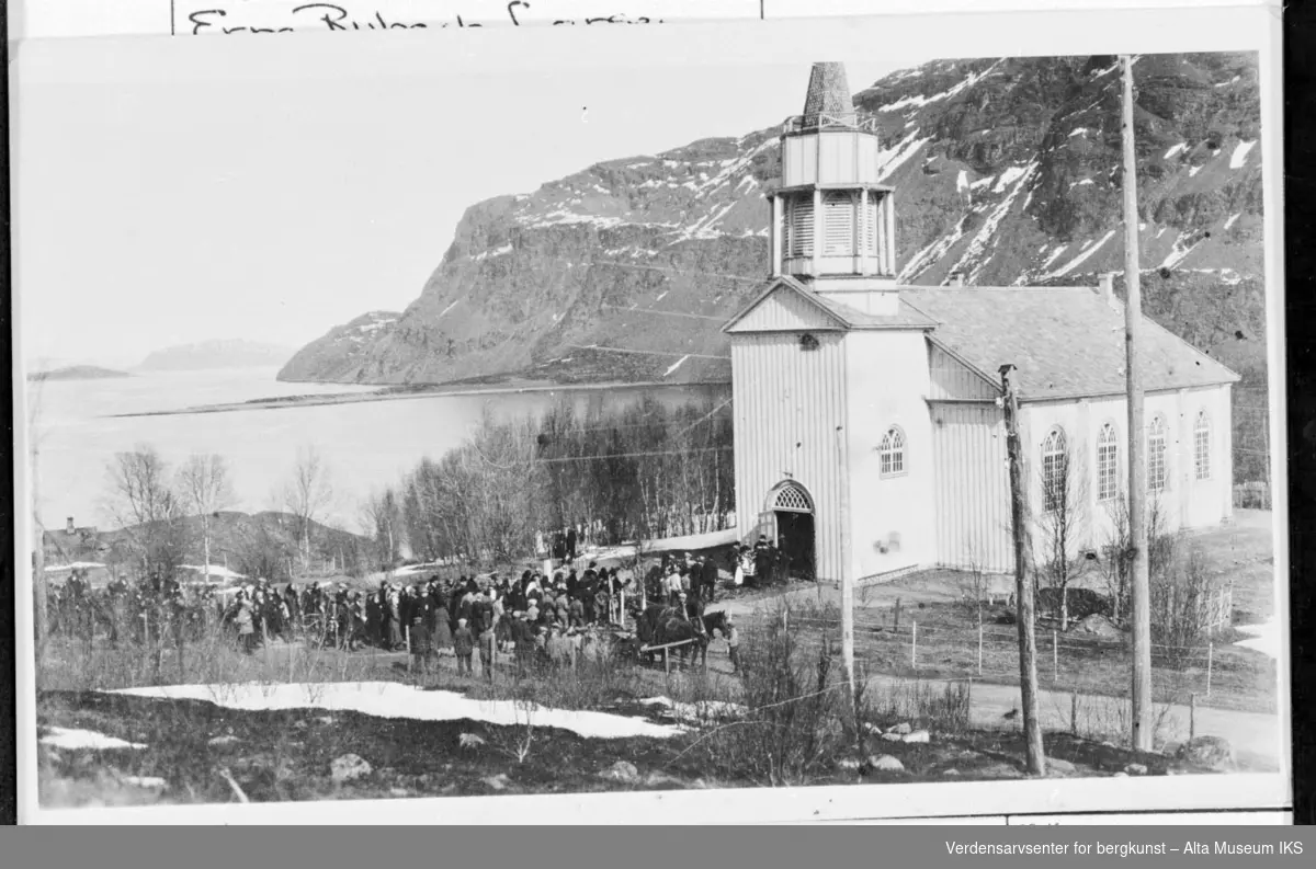 Begravelse i Kåfjord kirke. Stor folkemengde utenfor kirka og fjell i bakgrunnen.