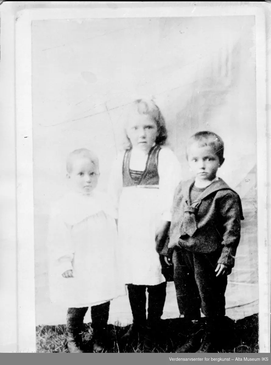 Gruppebilde av 3 barn kledd i kjoler og  matrosdress