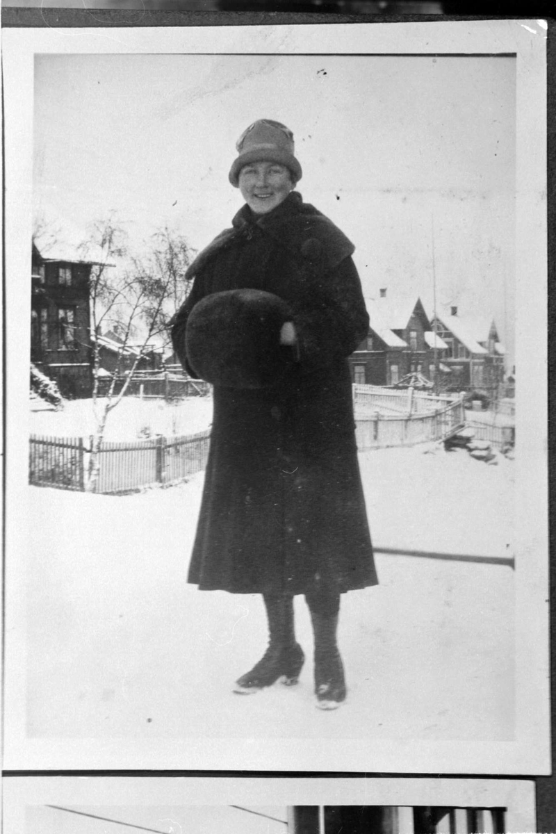 Vinterkledd kvinne med muffe stående i bygate.