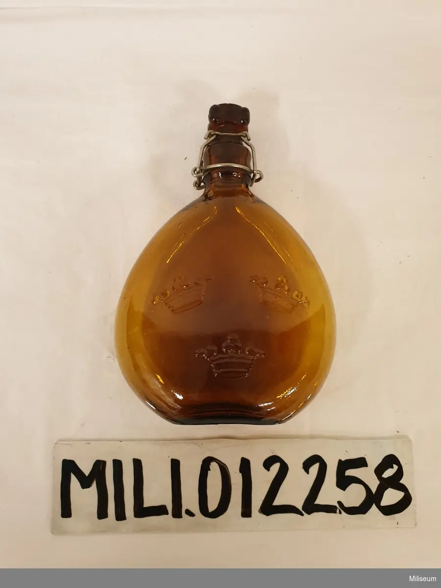 Dricksflaska m/1905 av brunt glas. 
Skruvkork av glas.