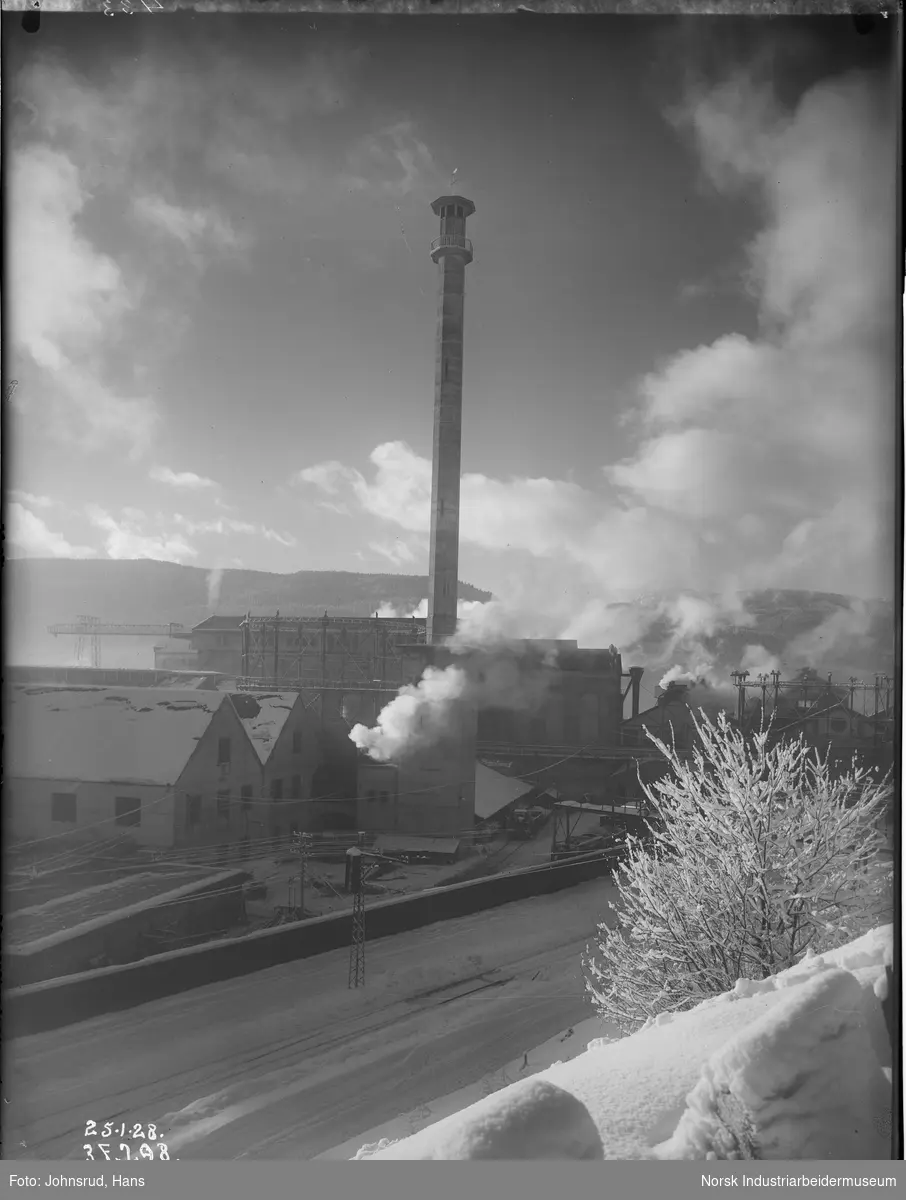 Luftinntakstårnet Hydrotårnet ("Minareten") sett fra Grønnbyen. Jernbanesporene langs fabrikken i front.