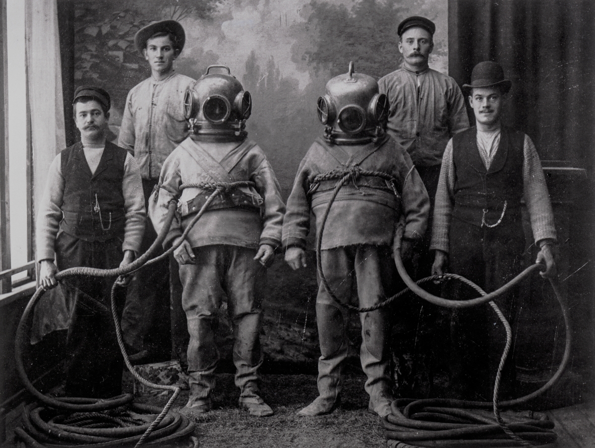 TUNGDYKARE
Skånska Cementgjuteriets dykare med hantlangare, fotograferade i ateljé i Vimmerby omkr. 1910