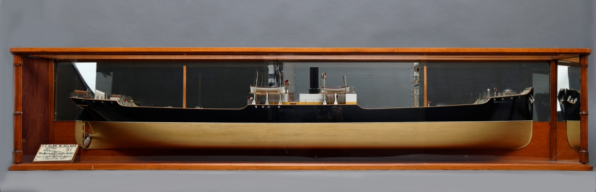 En halvmodell av et dampskipet "Saltwell", senere "Albr.W.Selmer", i en glassmonter til oppheng på vegg. På bakveggen i monter er det en speilvegg.