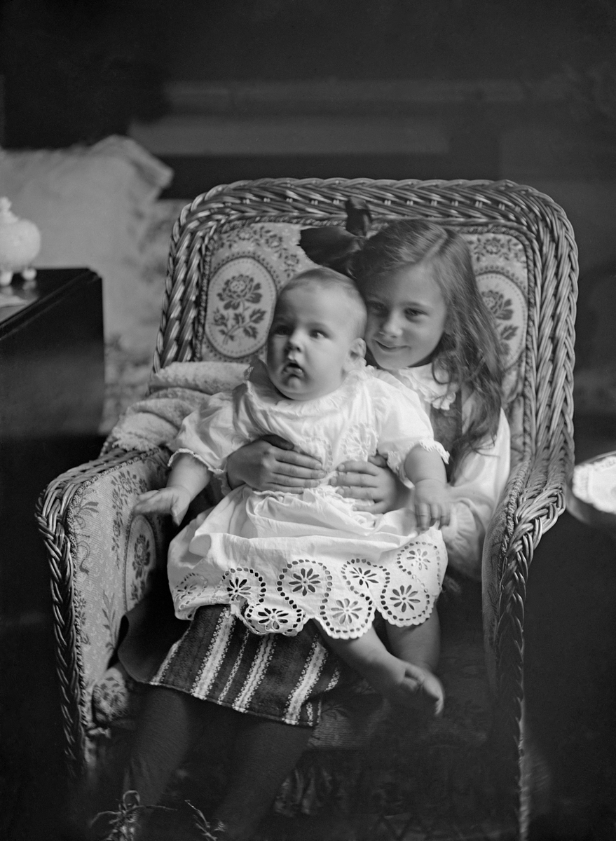 Porträtt av Anna Gabrielsdotter Spens med lillasyster Ulla i knäet. Bilden är tagen i flickornas hem Engelholm i Sankt Anna.