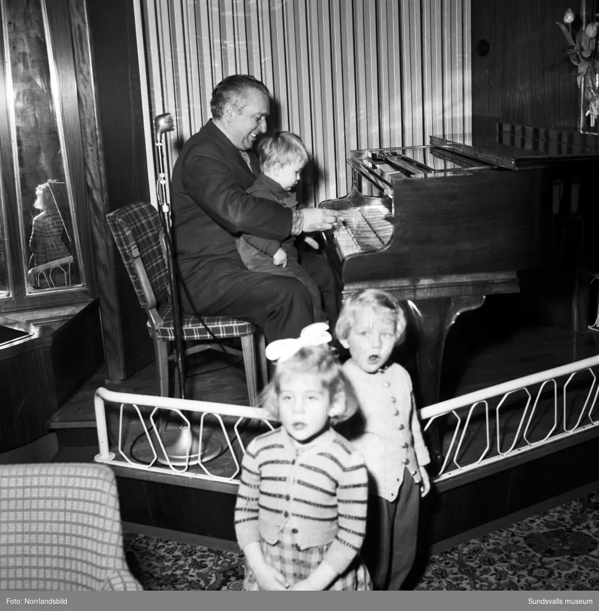 Konditori Terrassen på Tivolivägen 22. Pianisten Tony Ferraresi sitter vid pianot med ett litet barn i knät.