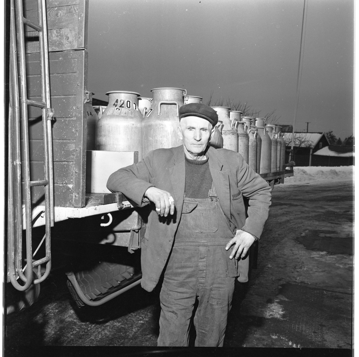 Åkeriägare Erland Andersson står lutad mot sin lastbild med mjölktunnor på flaket.