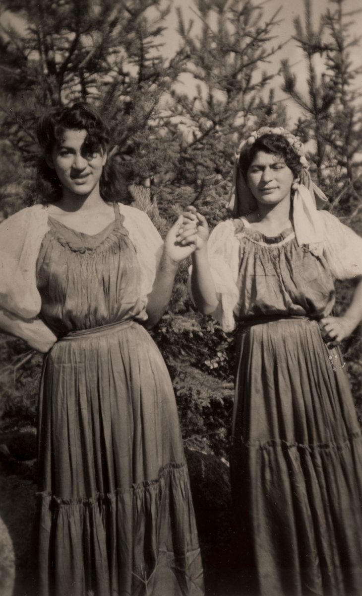 Två romska kvinnor mot en fond av granskogi Hofors. Fotografiet är taget söndagen den 30 juli 1950.
