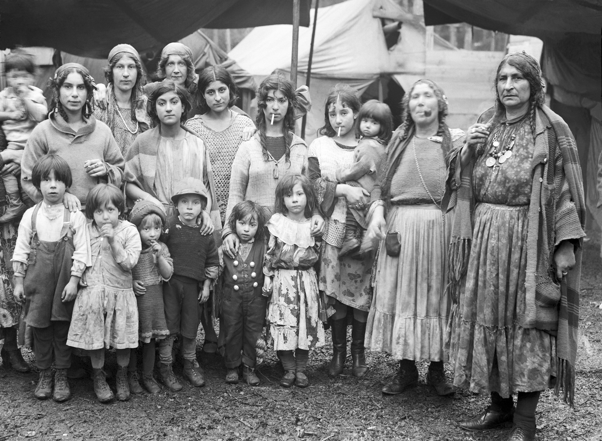 En grupp romska kvinnor och barn uppställda för fotografering. I bakgrunden syns tält. Boendestandarden bland svenska romer var under 1900-talets första hälft mycket varierande. Familjer som hade det bättre ställt kunde äga flera tält, medan fattigare familjer enbart hade ett tält. Man sov då där marken var minst lerig. Under 1940-talet förbättrades levnadsstandarden och flera svensk-romska familjer specialbeställde nu bostadsvagnar. Att inte behöva sova på marken utgjorde en avsevärd förbättring av livskvaliteten. Eftersom vagnarna specialbeställdes kunde beställaren vara med och påverka vagnens utformning. Ofta fanns sovgemaket längst in, varpå vardagsrummet följde och köket låg längst ut. Denna utformning kunde dock skilja sig åt mellan olika vagnar. Generellt var dock vagnarna dåligt isolerade och kalla att bo i. Först på 1960-talet tilläts svenska romer att bli bofasta.