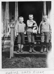 Tre små gutter, brødrene Gisleberg, står utenfor inngangen t
