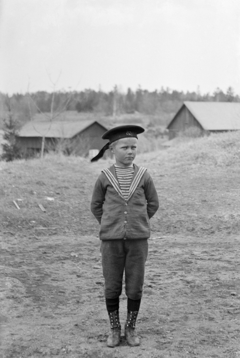 Fotograf Emil Durlings äldsta systerson Arne Hallin med ladugården till hemmet Ramsdal i bakgrunden. Son till Karl Johan Hallin och Durlings syster, Hedvig Maria Bertha Durling.
