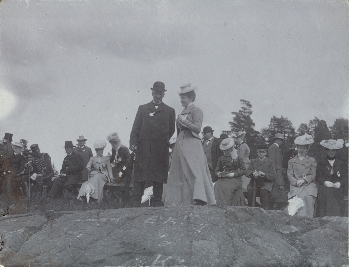 Text i fotoalbum: "Ränneslätt K 4 Kav. aspirantskola 1900". Samling av civila vid övningsplats.