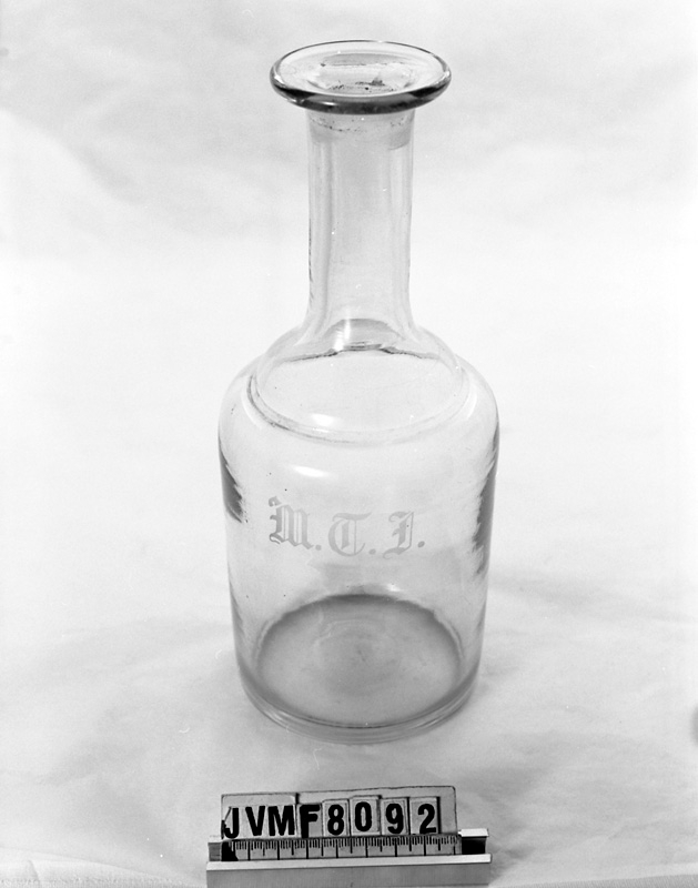 Vattenkaraff av klart glas, med initialerna MTJ ingraverat.