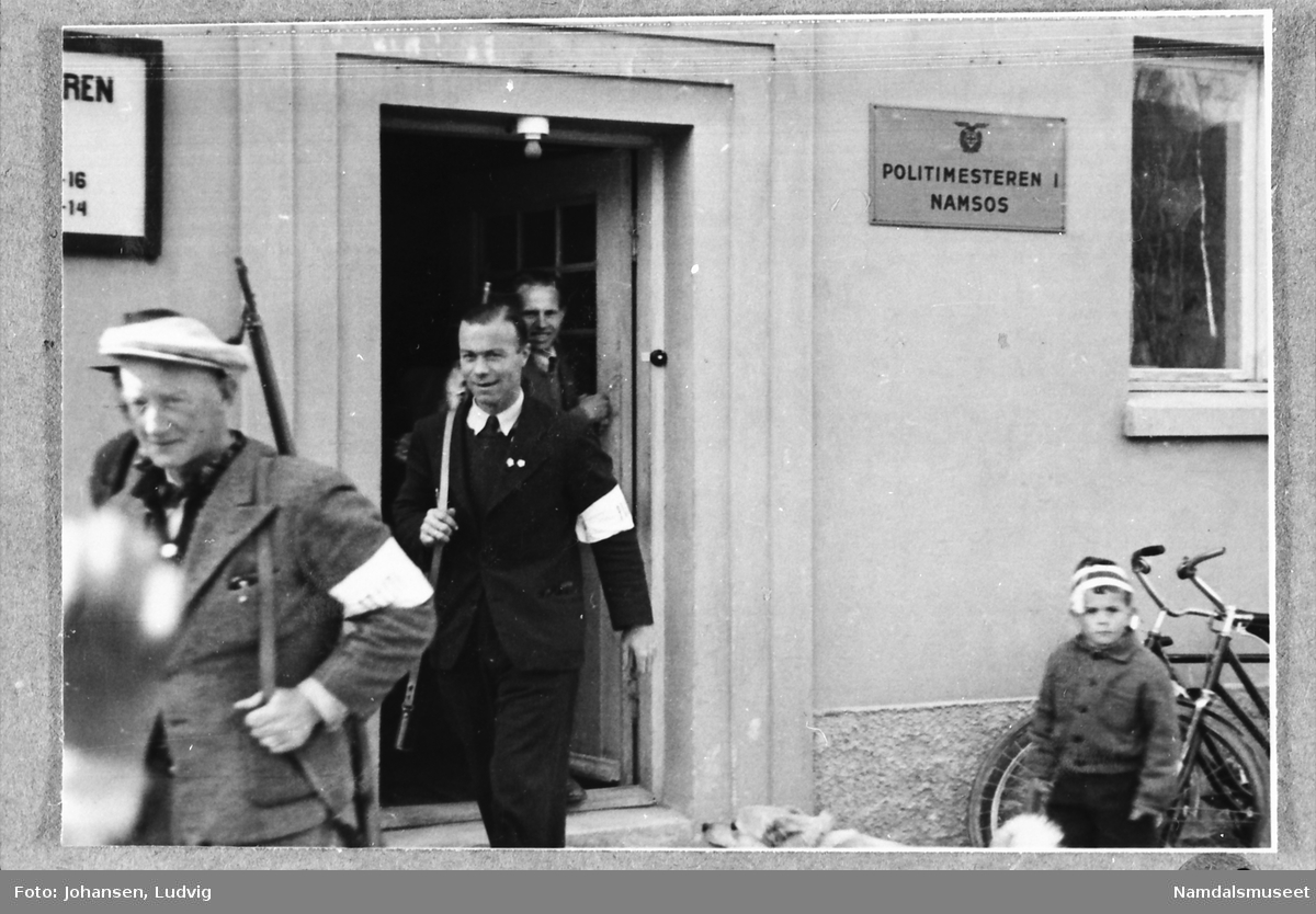 Namsos sentrum, Skolegata, Hakligården, 8. mai 1945. Nye polititjenestemenn går ut i arbeid med geværet over aksla.