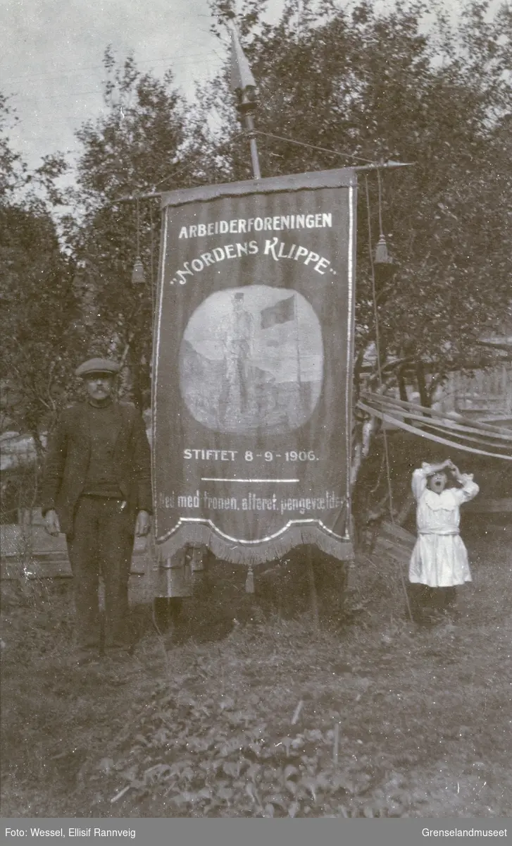Arbeiderforeningen Nordens Klippes fane fra 1907 med påskriften: Ned med tronen, alteret, pengevældet. Per Matson Nylander - foreningens tredje leder - til venstre.