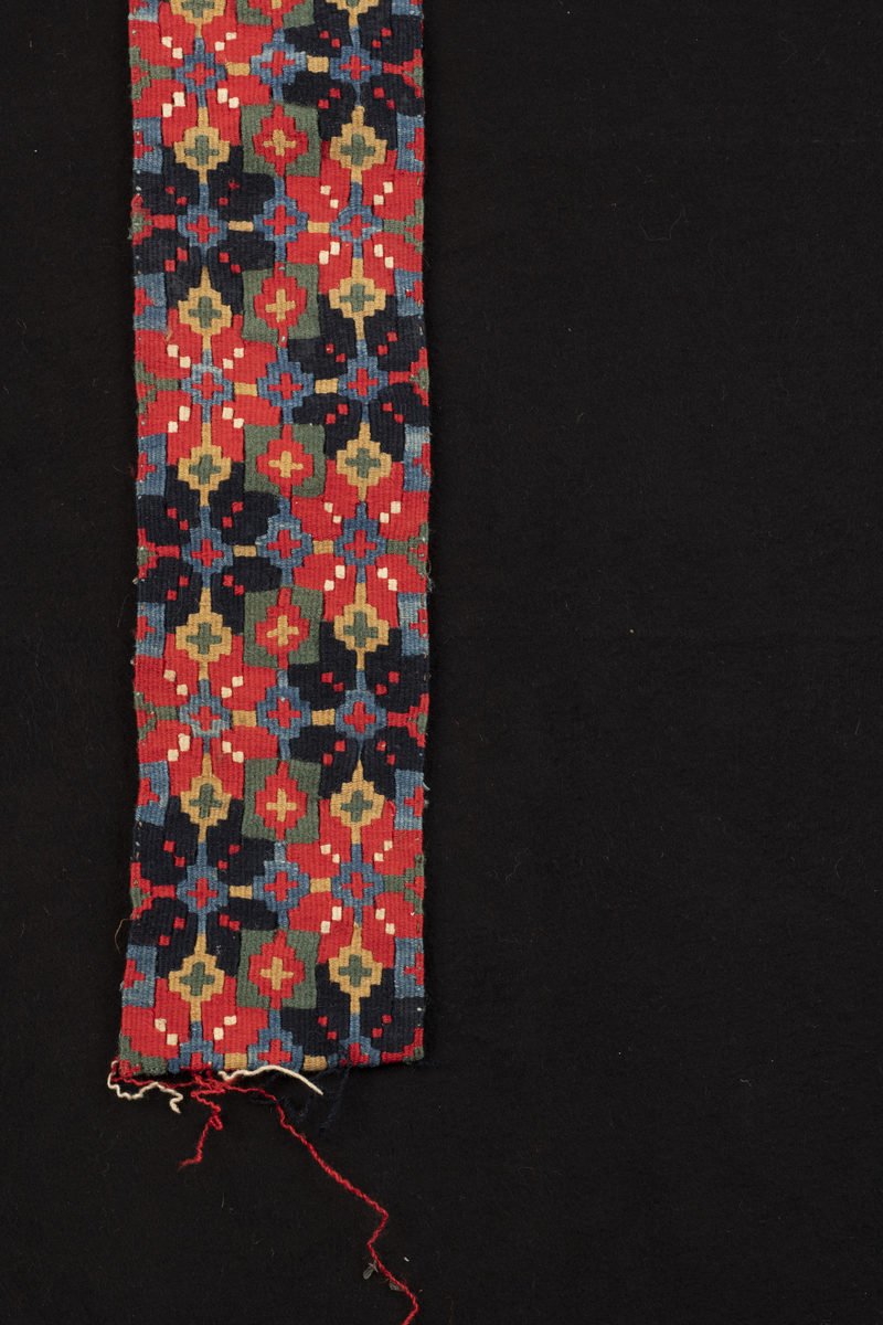Stakkebord i smettebandsveving. Mønster med to rader av åttebladsroser i vekselvis rødt og mørk blått. Borden var utstilt ved Noregs Bygdekvinnelags tekstilutstilling i Oslo, 1953.