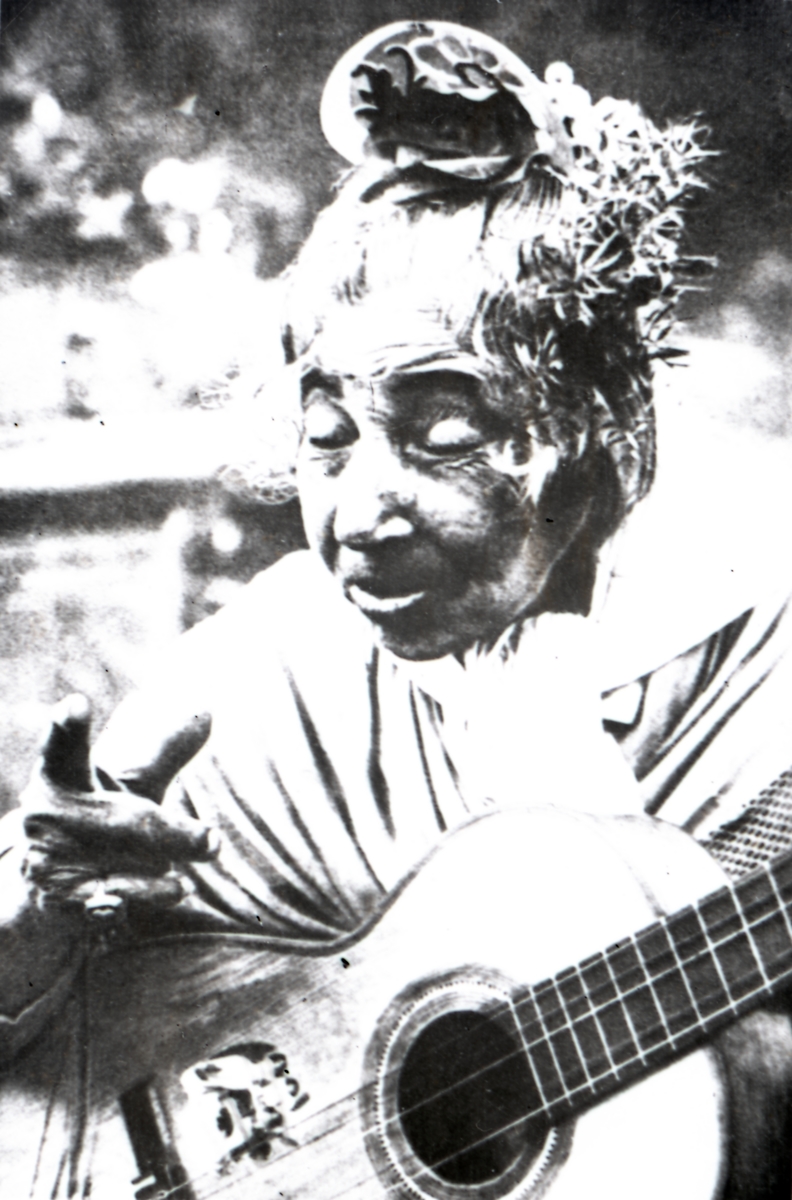En kvinna poserar för kameran med en gitarr. Bildens ursprung är okänt.
