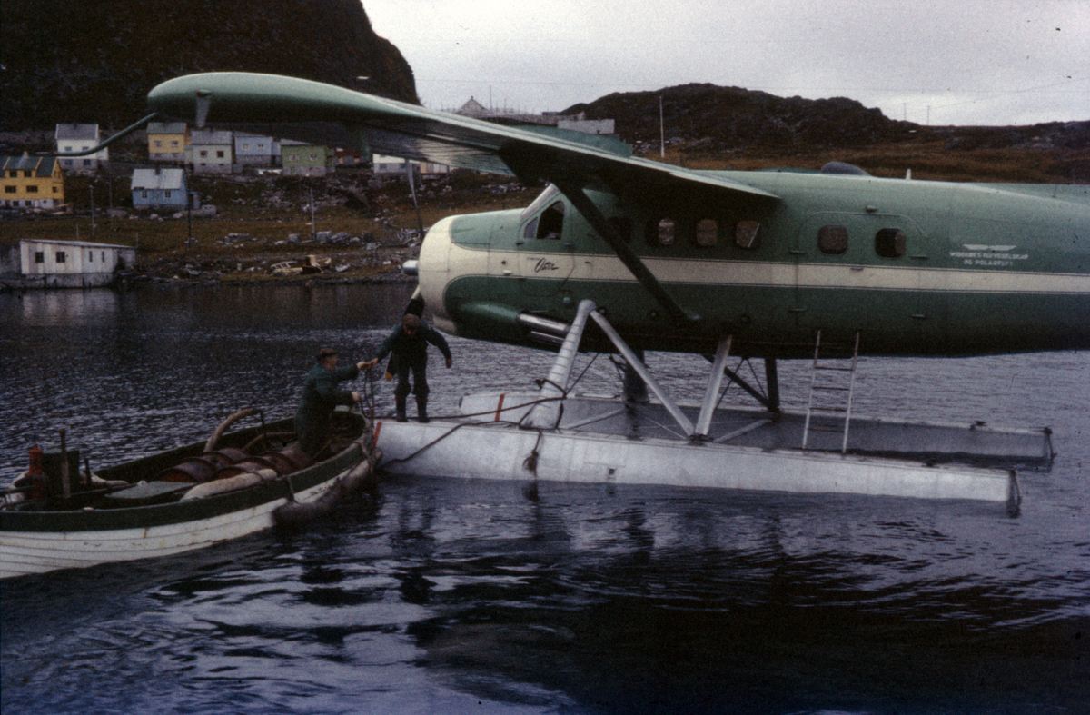 En sikringsbåt med drivstofftønner blir fortøyd til et av Widerøes Flyveselskap & Polarflys DHC-3 Singel Ottere.