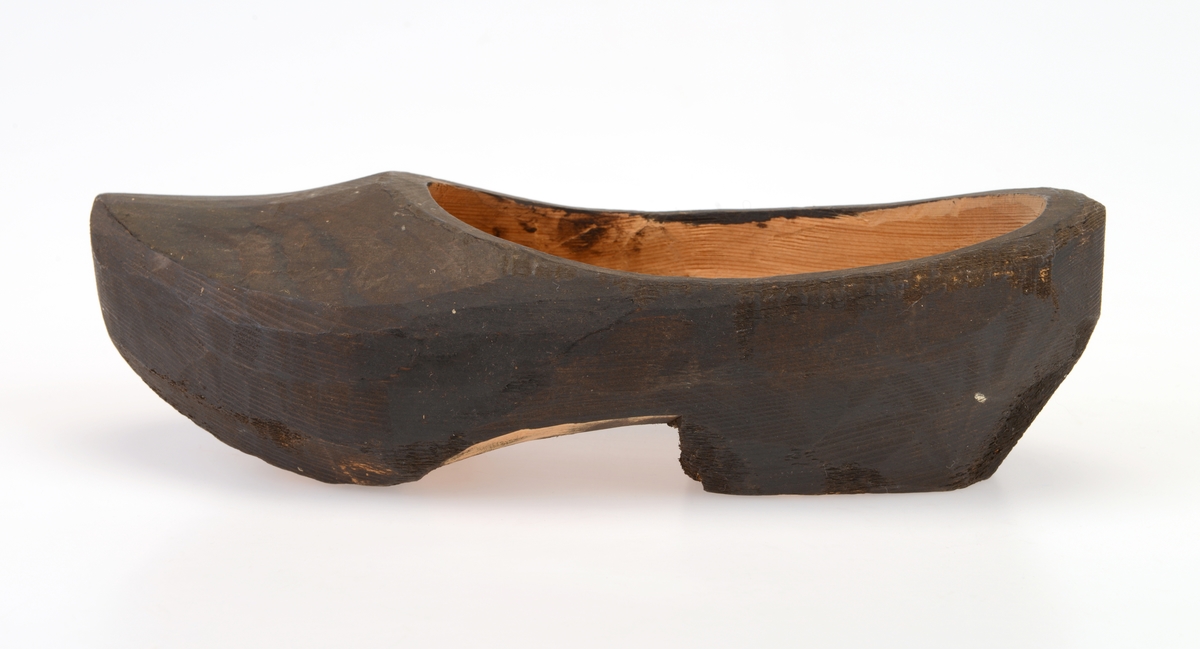 En tresko laget av ett trestykke (helskåret). Den er muligens laget av furu. De er trehvite innvendig og under. Utsiden er svartfarget, muligens etter at de er satt inn med tjære. Treskoen har hælkappe og foran er de spisse. Skoen har en lav hæl.