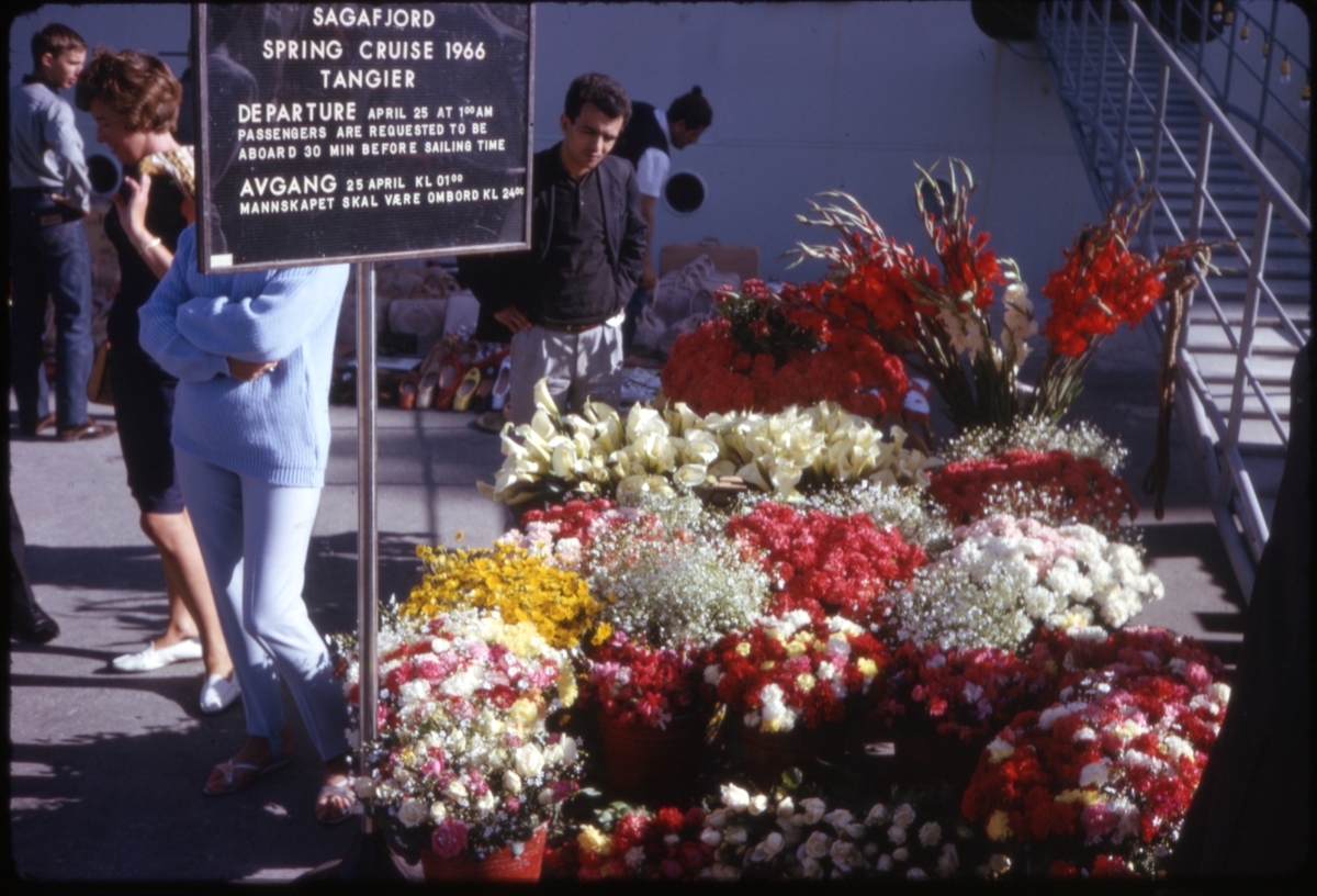 Blomster og mennesker foran cruiseskipet 'M/S Sagafjord' ved kai i Tanger, Marokko. 'Sagafjord' Spring Cruise to Europe 1966.