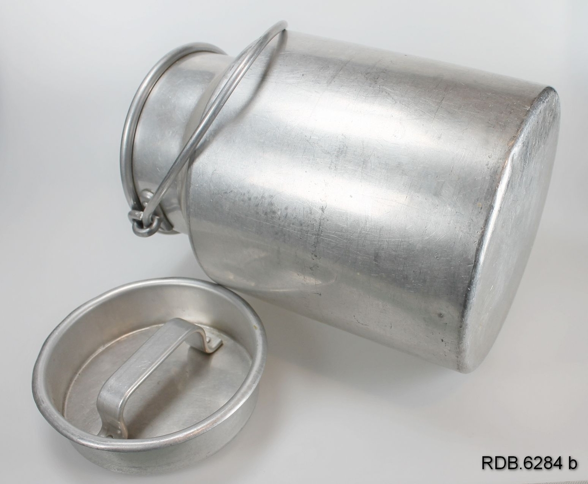 Sølvfarget aluminiumsspann med hals, hengslet hank og løst lokk med håndtak.