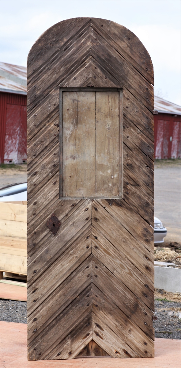 Døra er laget av 1 1/4 toms planker med to enkle drev som holder plankene sammen. Døra er belagt med profilert panel. Panelet er lagt på skrå i mønemønster og festet med spiker som har digre hoder. Døra har et vindu på 45 cm x 79 cm som innvendig er lukket med en liten hengslet dør. Døra er nærmest halvsirkelformet i toppen og passer da inn i buen i murverket. Låsen sitter på og har rombeformet nøkkelhullbeslag og to solide gangjern med to enkle knuter. Låsen sitter på innsida og er helt innebygd med jernplater og to slåtter. På innsida er rester etter påmalt marmorering.