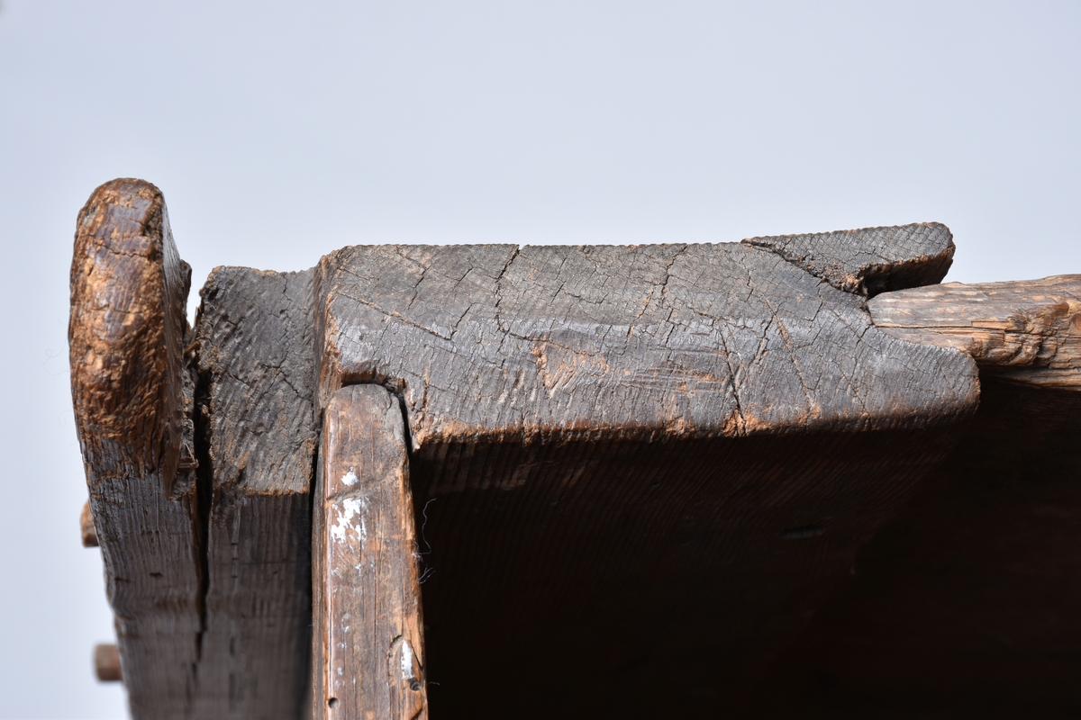 Rotekista av trä. Rektangulär med på bredsidorna inristade drakslingor, ändarna är prydda med prickade och släta rutor.