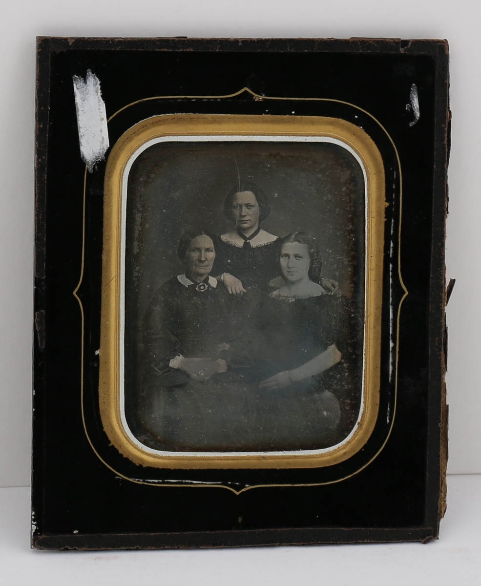 Daguerreotypi av tre kvinner. Én står i midten bak to som sitter.