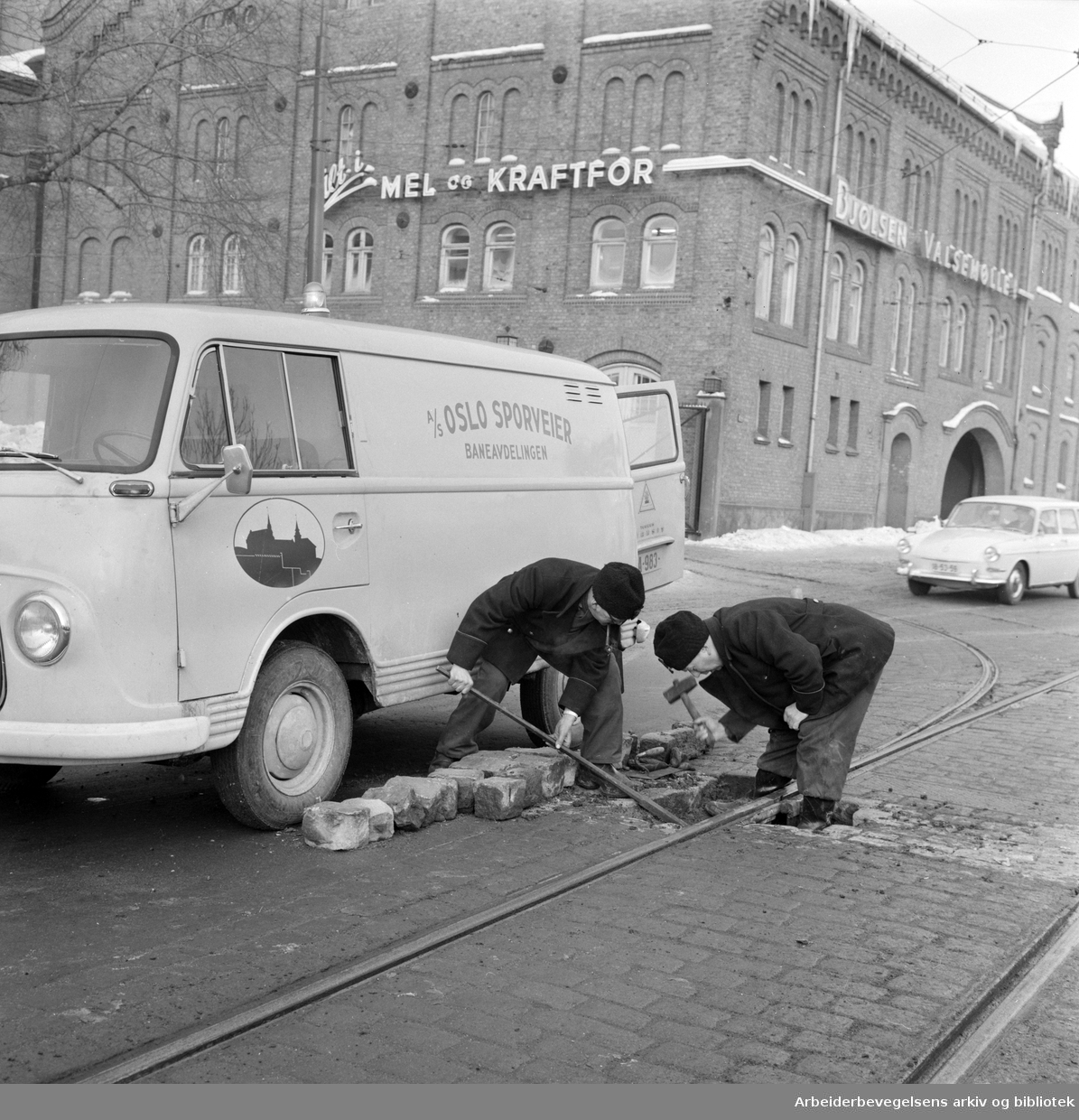 Sporveisarbeiderne Reidar Thomassen (til venstre) og Sverre Holte fra Oslo Sporveiers baneavdeling reparerer en av linjeskjøtene utenfor Bjølsen Valsemølle på Sandaker. Januar 1966.