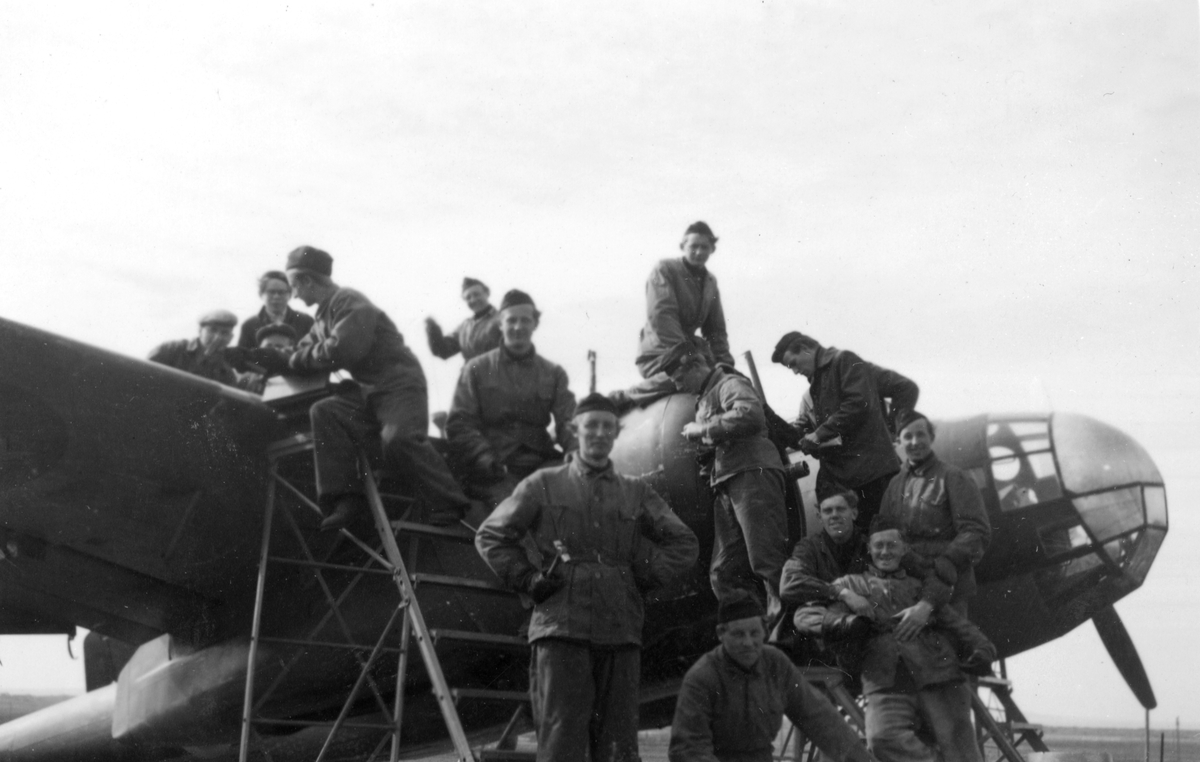 Flygmekaniker samlade vid flygplan Saab B 18 i samband med reparationsarbete efter haveri vid Fyllebro utanför Halmstad, 1940-tal.