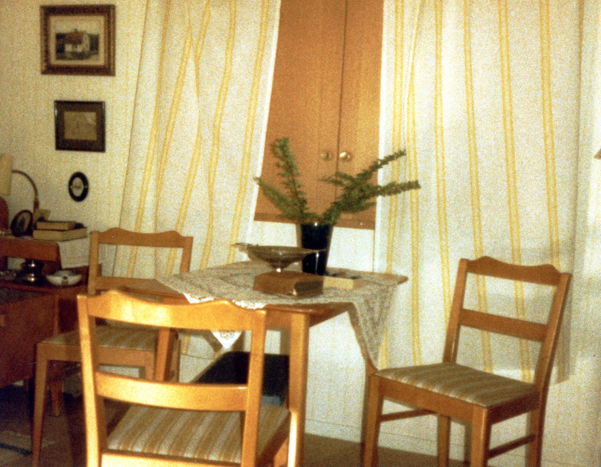 Brattåsgården vid invigningen år 1986. Utställning av föremål från gamla Brattåshemmet, gjord av Kållereds Hembygdsgille. Delar av föremålen finns nu på Mölndals stadsmuseum. Här ses ett litet fyrkantigt bord och tre stolar, allt i ljust trä.