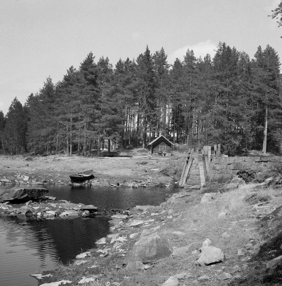 Vestsjødammen ved Vestsjøen, Våler i Solør, Hedmark. Fløterkoie i bakgrunnen. Lukedam, koie, robåt.