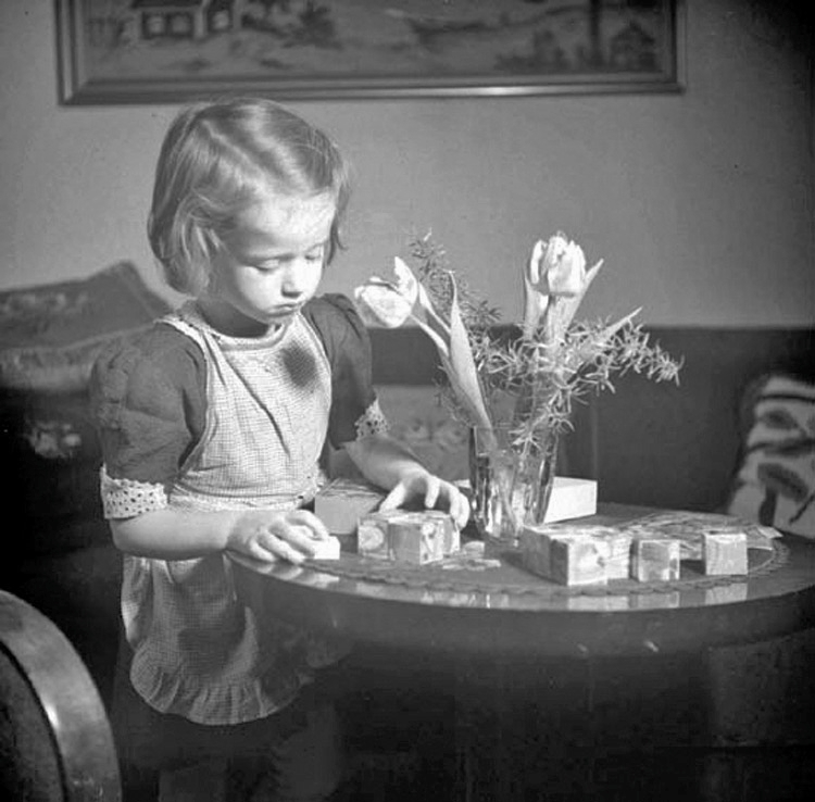 En flicka lägger puzzel av målade träkuber.