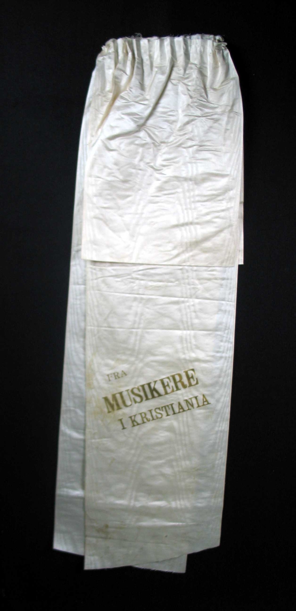 Begravelsessløyfe i mønstret hvit silke med tekst i gull.