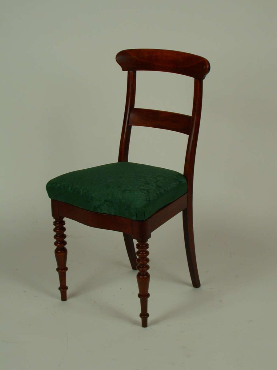 Brunbeiset stol med stoppet sete. Stoffet i setet er grønt.  Stilen er en blanding av biedermeier og historisme.