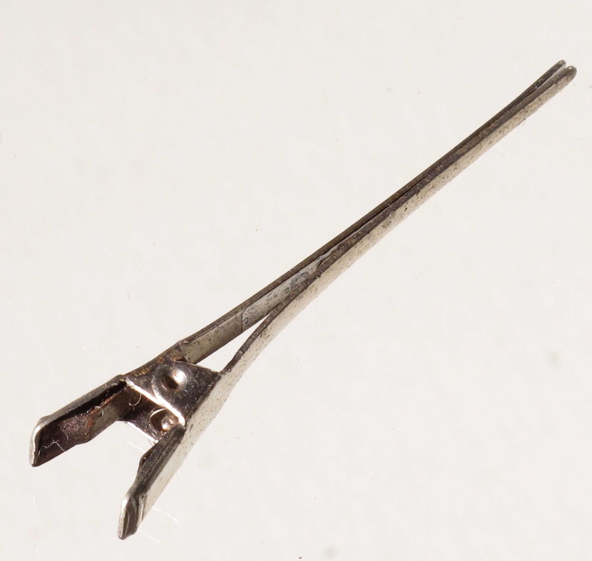 Metallspenne bestående av to deler med en liten fjær mellom "håndtakene" som holder spennen lukket.  Blikk