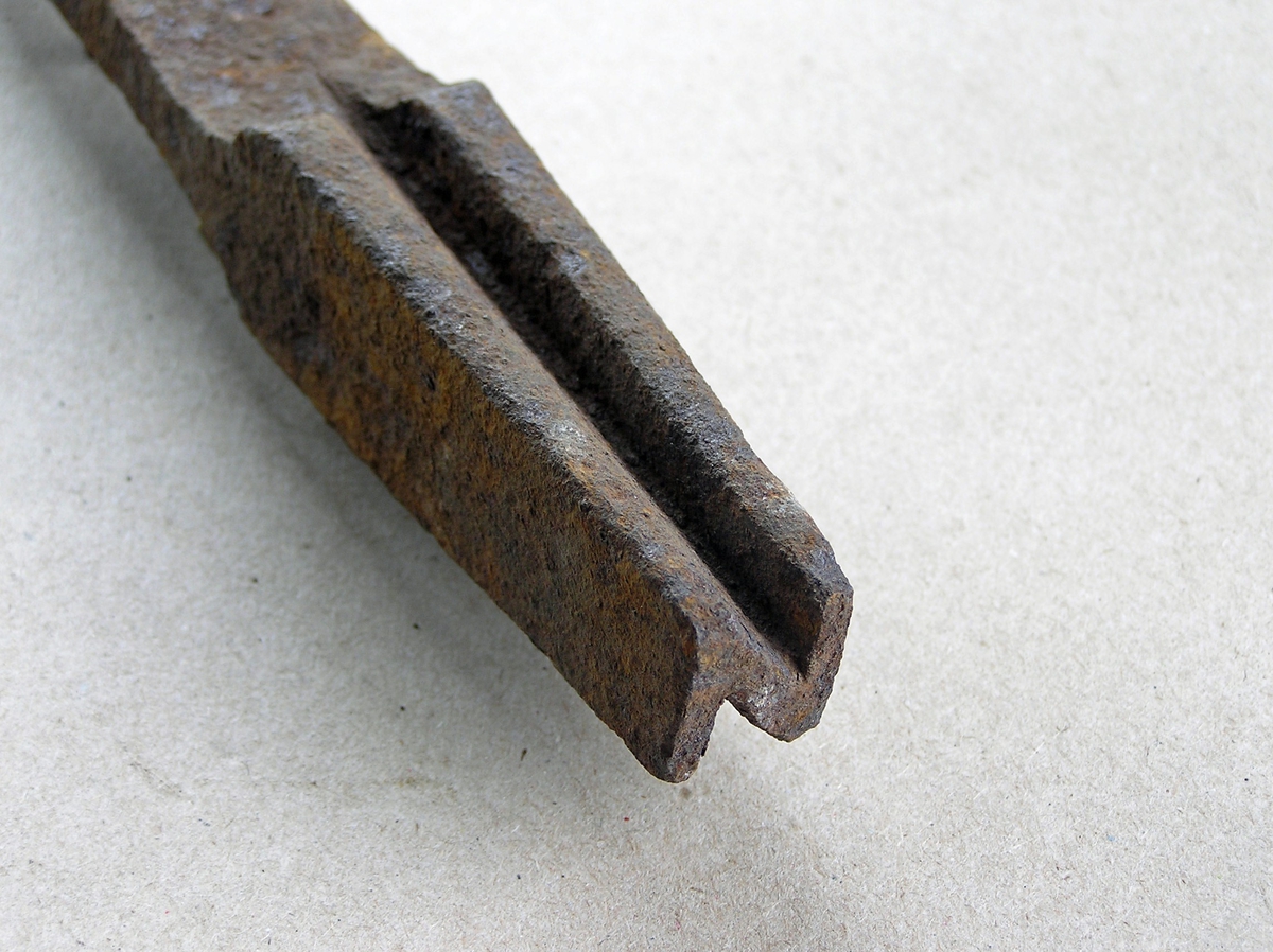 Smidd jernstykke til bruk ved smiing av merkeøks. Merket ble formet rundt stempelet. Stempeldel og håndtak i ett. N-formet stempel. Noe rust.
