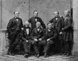 Sju herrer i dress(tre eldste sittende foran)