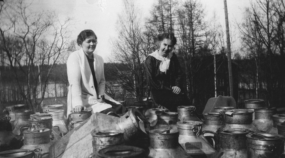 To kvinner med tomme melkespann på perrongen
