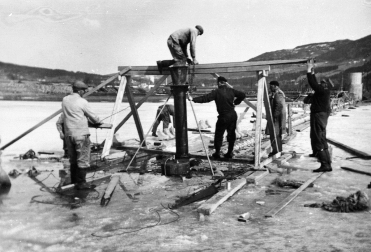 Bygging av vanninntak, pumpestasjon, inntaksil settes på plass, Hedmark Tørrmelk, Tine, Brumunddal. 8 menn arbeider.