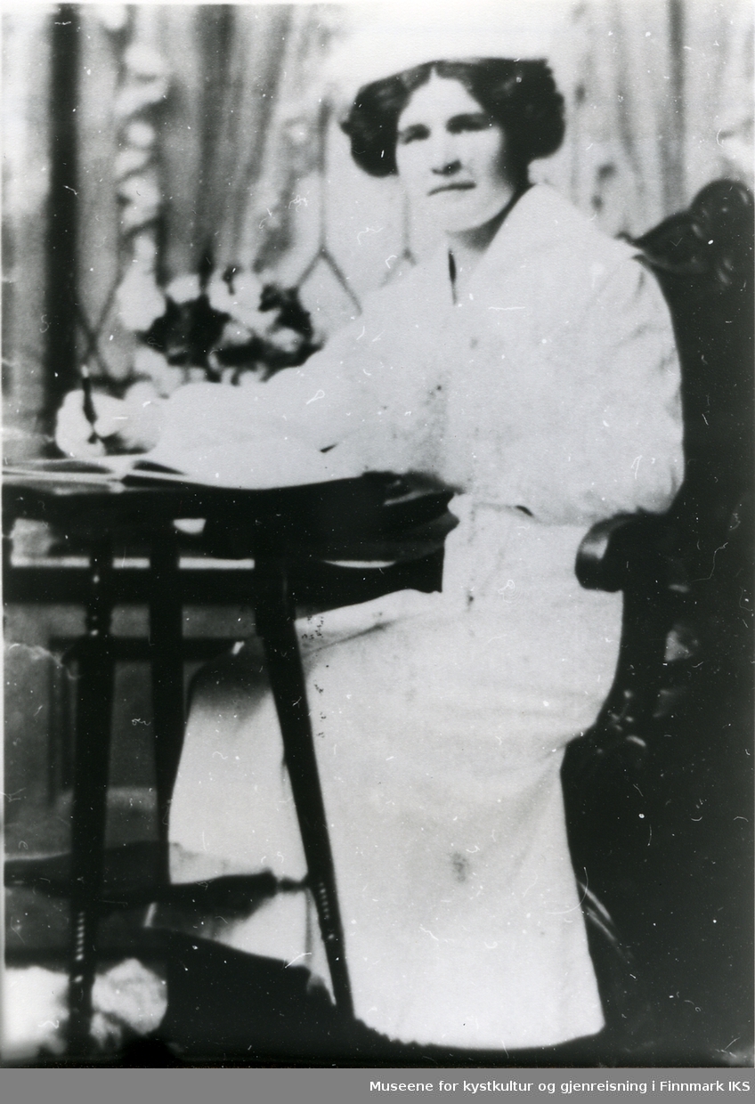 Julianne Helene Jörgensen fra Sandfjorden sitter ved et bord. Ca 1920.