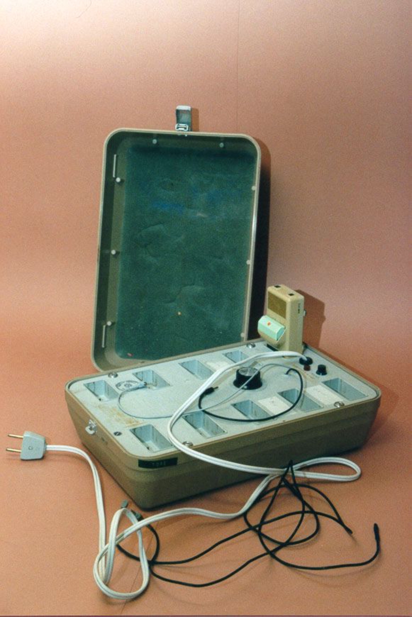 FM-anlegg, i boks, med 2 mikrofoner og 9 høreapparater
Hvit tape på lokket: Påskrevet "NERMO SKOLE"