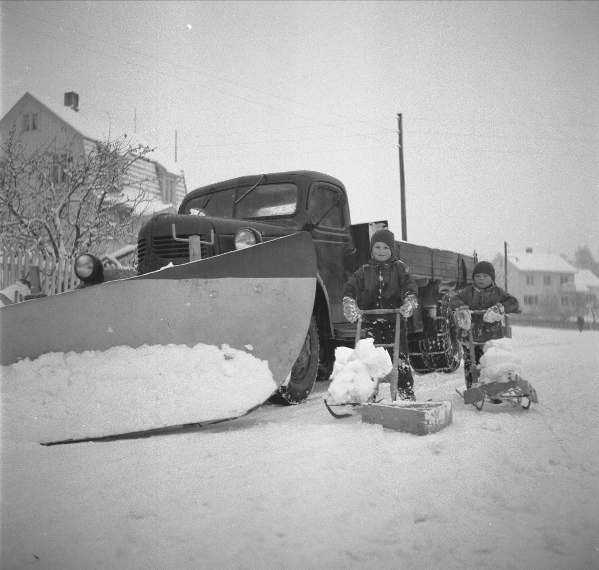 Lastebil, brøytebil, Syver Andersens gate, Hamar. Dodge eller Fargo årsmodell 1946-47. Lastebilen tilhørte  Arne Holstein. Gutter med snøplog, spark, f.v Claus Myrmoen, Morten Johnsen.