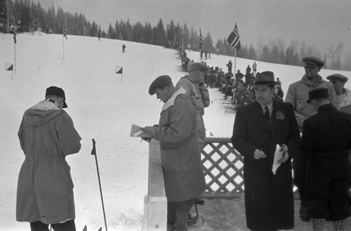 NM. Norgesmesterskap på ski, langrenn på Høsbjør i Furnes 1949. Skisport. Vinteridrett. H. K. H. kronprins Olav studerer programmet på ærestribunen på skistadion
