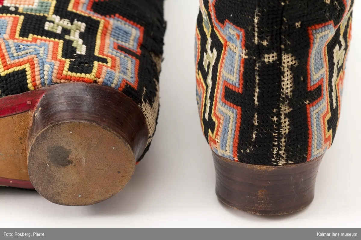 KLM 9011. Skor, stövlar, ett par. Stövlar i svart tyg med broderier i blå, röd, gul, grön, rosa, orange och grå färg. Fodrade med rött läder. Klack, 3 cm. Kan sannolikt dateras till 1870-tal.
