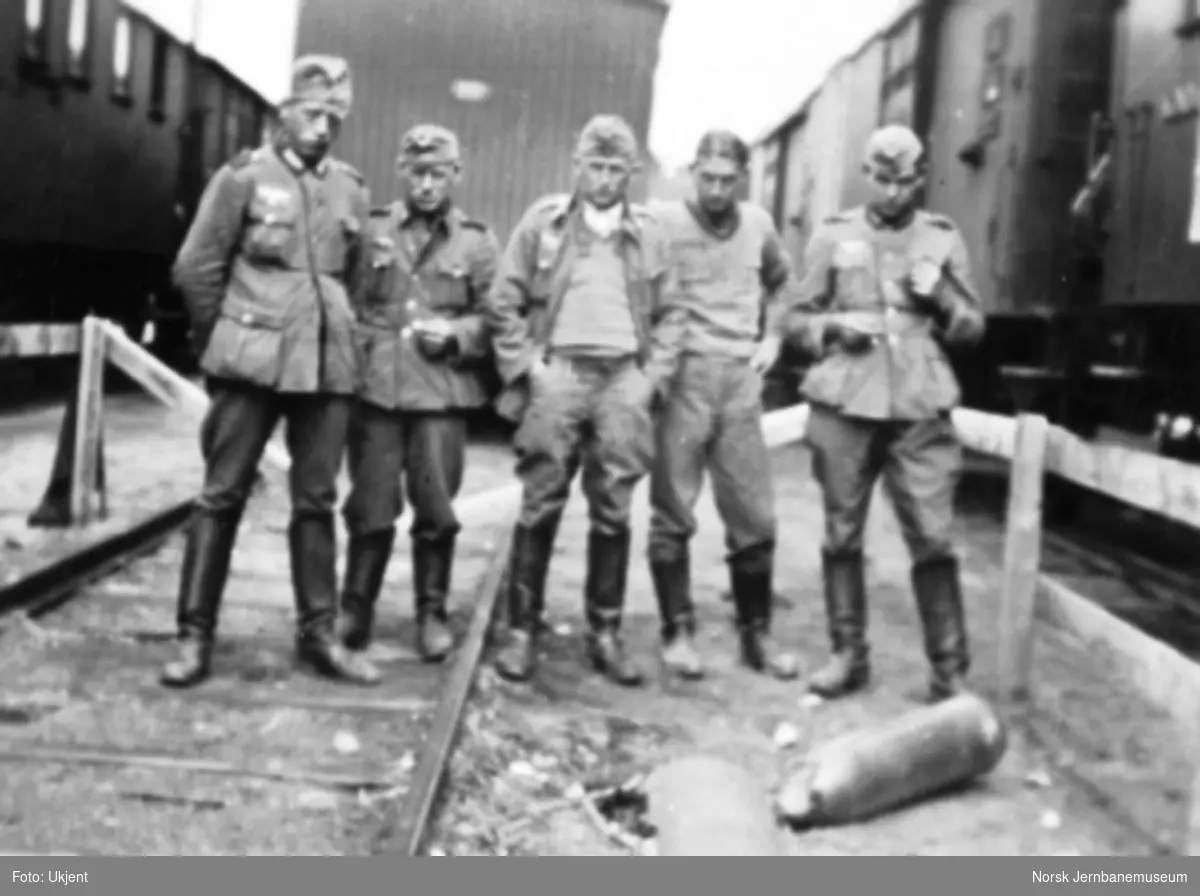 Dombås stasjon etter bombingen i april 1940; soldater ser på en udetonert bombe