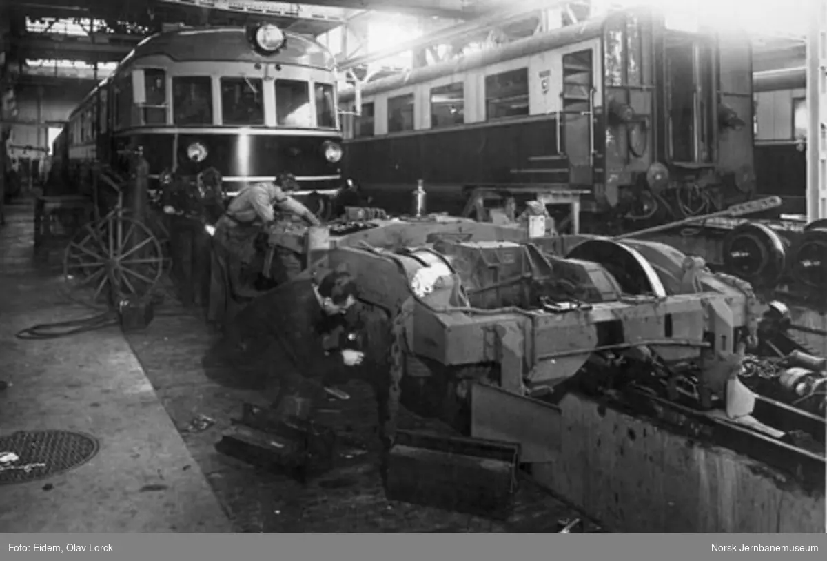 Fra lyntoghallen i Lodalen med ekspresstogsett av type 66 og 88 : verkstedarbeidere arbeider med en motorboggi til type 66